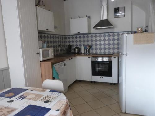 Elle comprend une petite cuisine équipée d'un réfrigérateur blanc et d'une table. dans l'établissement Maison Atypique pêcheur DIEPPE 6 personnes et bébé proche bord de mer, à Dieppe