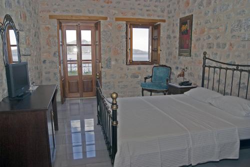 1 dormitorio con 1 cama, TV y silla en Smyros Resort, en Poulithra