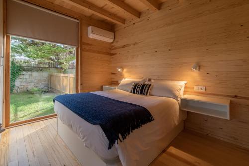 1 dormitorio con 1 cama en una pared de madera en Cabanas Narea en Laxe