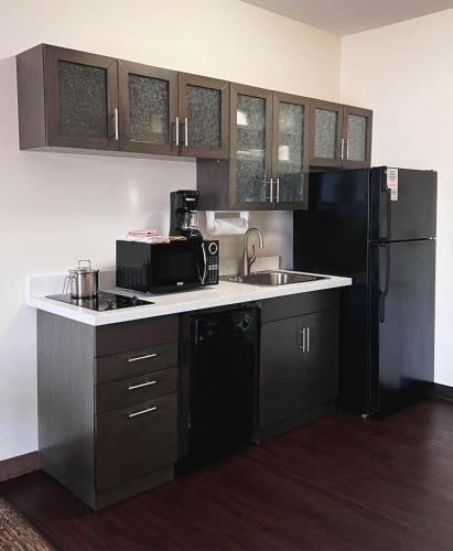 a kitchen with a sink and a black refrigerator at Candlewood Suites Olathe by IHG in Olathe