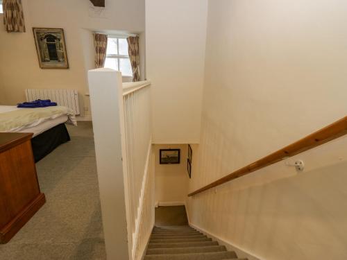 eine Treppe in einem Zimmer mit einem Bett und einem Fenster in der Unterkunft Longlands Groom's Quarters in Cartmel