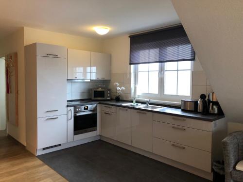 a kitchen with white cabinets and a white refrigerator at Ferienwohnung "Kranich" im Ferien-Resort Rügen in Sagard