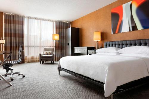 um quarto de hotel com uma cama grande e uma cadeira em Sheraton Charlotte Hotel em Charlotte