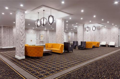 a waiting room with orange chairs and tables at Sheraton Charlotte Hotel in Charlotte