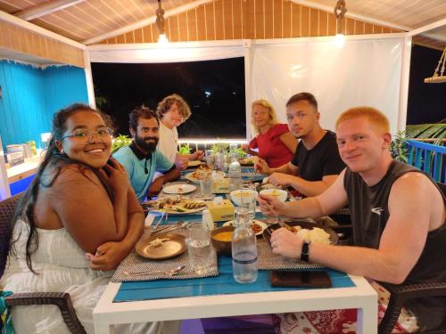 a group of people sitting around a table eating food at Koimala Hotel in Maamigili