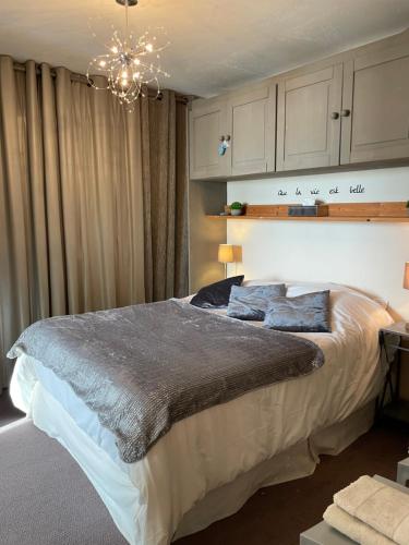 Un dormitorio con una cama grande y una lámpara de araña. en Maisonnette vue panoramique lac d'Annecy, en Veyrier-du-Lac