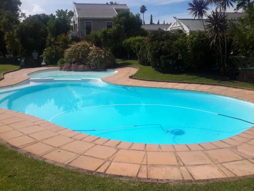 a large blue swimming pool with a brick walkway around it at Island Nest in Knysna