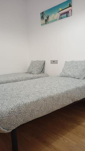 two beds in a bedroom with a picture on the wall at Apartamento Area Maior in Malpica