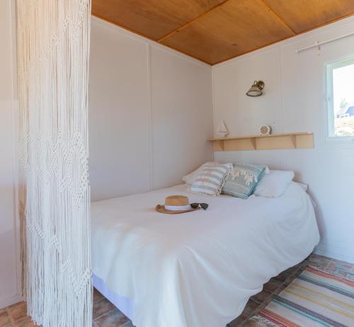 sypialnia z białym łóżkiem z kapeluszem w obiekcie Navigateur Ste-Luce w mieście Sainte-Luce
