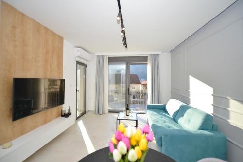a living room with a blue couch and a tv at Solaris Lux Apartments in Kotor