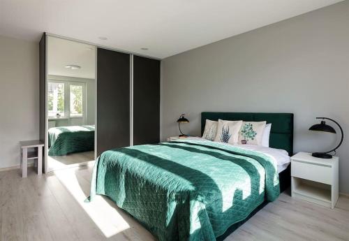 - une chambre avec un grand lit et une couverture verte dans l'établissement Green bed by the pine forest, à Anykščiai