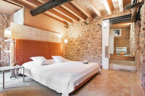 a bedroom with a large white bed and a stone wall at Refugio Son Pons in Campanet