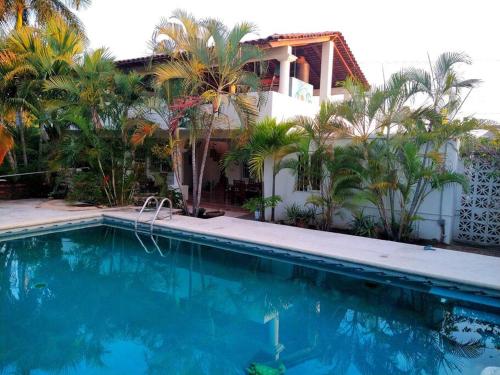 a swimming pool in front of a house with palm trees at Lush Garden House near beaches with private pool. in Puerto Escondido