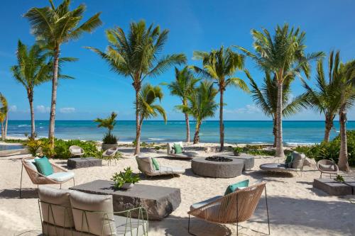 a beach with chairs and palm trees and the ocean at Impression Moxché by Secrets - Adults Only in Playa del Carmen