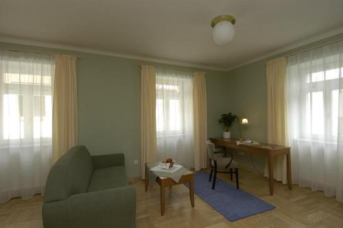 a living room with a couch and a desk and windows at Pension Křivá in Olomouc