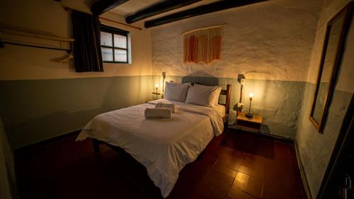 a bedroom with a large bed with white sheets and a window at Hotel Aceitunos in Villa de Leyva