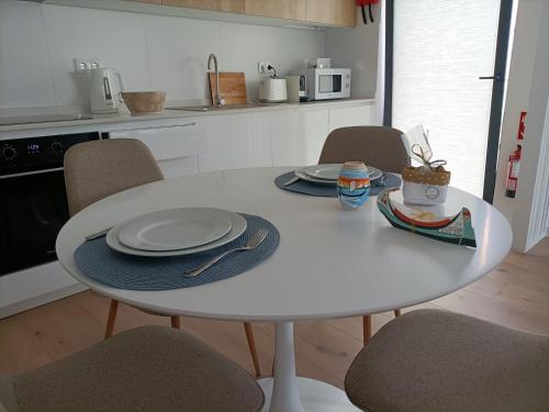 une table et des chaises blanches dans une cuisine avec une table et des assiettes dans l'établissement AVEIRO WONDER STAY, à Aveiro