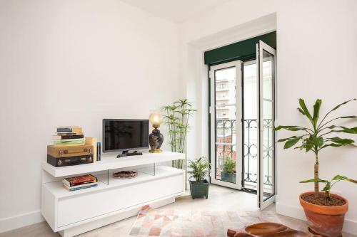 a white living room with potted plants and a tv at High on Lisbon in Lisbon