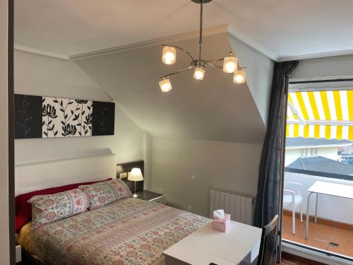 a bedroom with a bed and a table and a window at Habitaciones en chalet con jardín in Boó de Piélagos