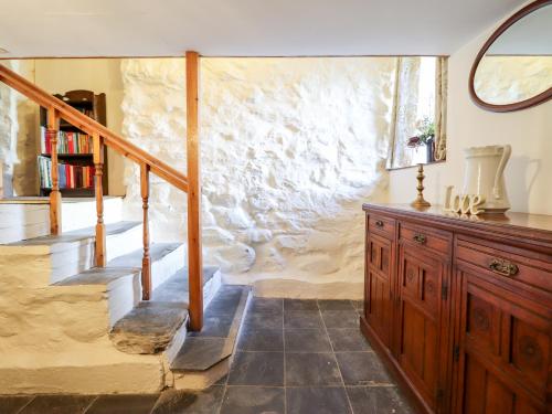 Habitación con escalera y pared de piedra. en Hen Argoed Cottage, en Llanbedr