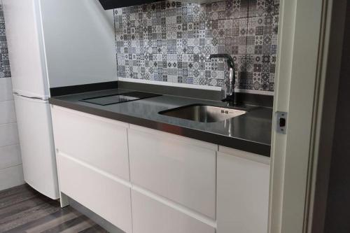 a kitchen with white cabinets and a sink at Alojamiento Marmar in Úbeda