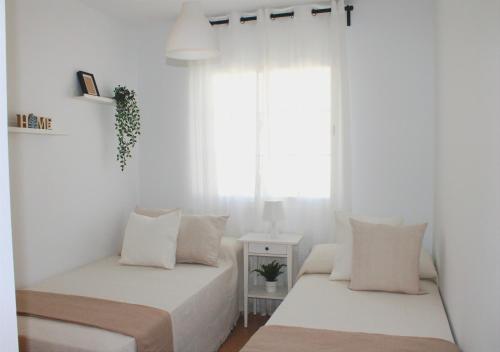 2 camas en una habitación con paredes blancas y ventana en Niza Mar, en Vélez-Málaga