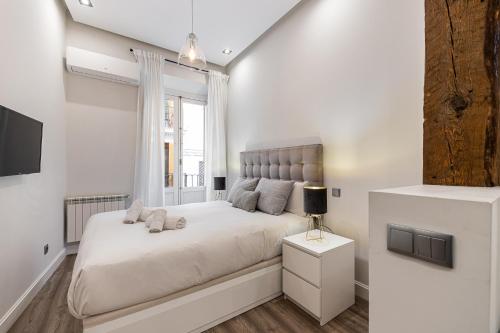 Un dormitorio blanco con una cama grande y una ventana en BNBHolder Living LA LATINA, en Madrid