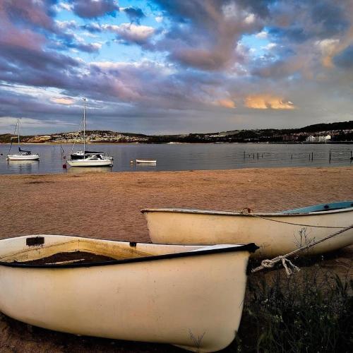 two boats sitting on the shore of a beach at luxury 2 bed apartment, sea view, near the beach. in Llandrillo-yn-Rhôs