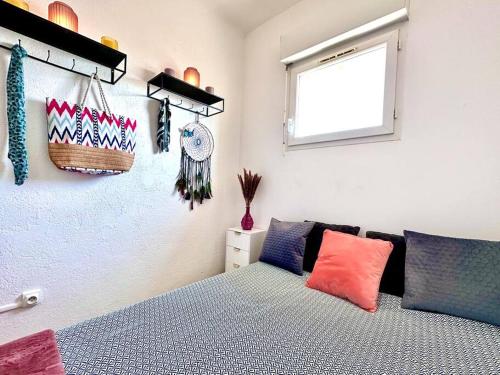 - une chambre avec un lit doté d'oreillers colorés et d'une fenêtre dans l'établissement Le Coin de Mer 2, Bord de mer, Plage 30m, Cosy, CLIM, Wifi, 4 personnes, à Fos-sur-Mer