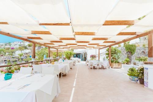 un ristorante con tavoli bianchi e sedie bianche di Hotel Ferdinando Beach & Thermal Spa a Ischia