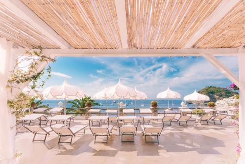 a room with a view of the ocean and tables and chairs at Hotel Ferdinando Beach & Thermal Spa in Ischia