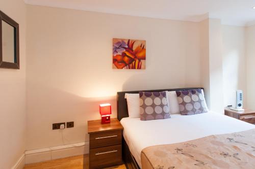 a bedroom with a bed and a night stand with a clock at London Serviced Apartments in London