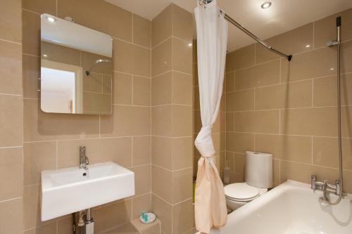 a bathroom with a tub and a sink and a toilet at London Serviced Apartments in London