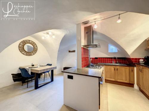 a kitchen with a sink and a table in a room at L’ Échappée Cachée - Gîte de Charme in Saint-Étienne-de-Fontbellon