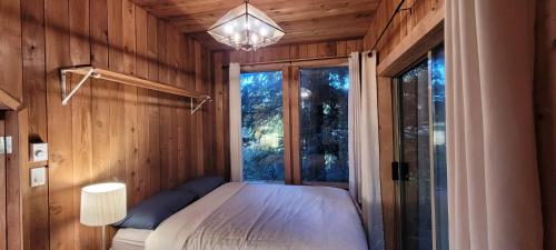1 dormitorio con 1 cama en una habitación con ventana en Ocean Views & Sunset Beach Cabin with soaker tub & fire pit en Powell River