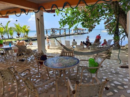 a patio with a table and chairs and a hammock on the beach at Villa Bella in Portobelo