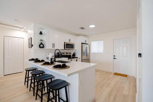 une cuisine avec des placards blancs et un comptoir avec des tabourets dans l'établissement The Pass Through Brand New 2 - 1 Modern Villa, à Homestead