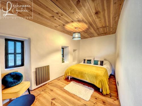 a bedroom with a bed and a wooden ceiling at L’ Échappée Cachée - Gîte de Charme in Saint-Étienne-de-Fontbellon