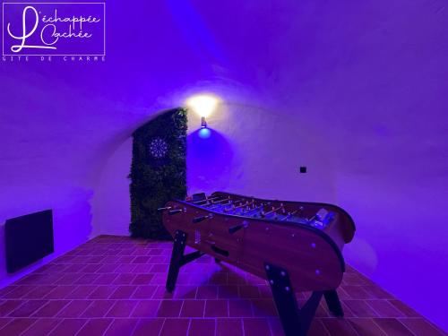 a ping pong table in a room with purple lighting at L’ Échappée Cachée - Gîte de Charme in Saint-Étienne-de-Fontbellon