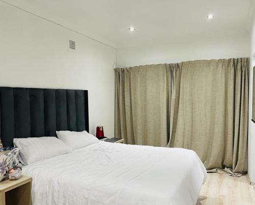 ein Schlafzimmer mit einem großen weißen Bett und einem Fenster in der Unterkunft Stay In Carlazo - Unlimited WiFi, Solar backup in Roodepoort