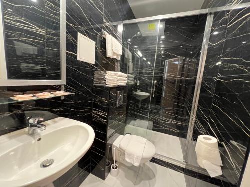 a black tiled bathroom with a sink and a shower at Hipotel Paris Printania Maraichers in Paris