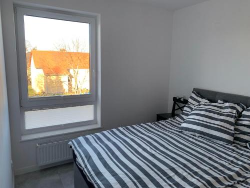 een slaapkamer met een gestreept bed en een raam bij Apartament Cieplice in Jelenia Góra