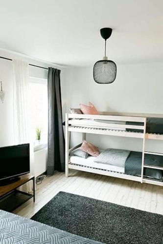 ein Schlafzimmer mit einem weißen Etagenbett und einem TV in der Unterkunft Modernes Apartment mit Balkon free Parking Netflix in Celle