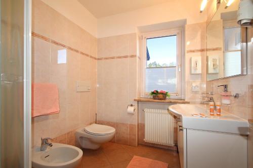 a bathroom with a toilet and a sink and a window at Hotel Garni Savoy - new opening in Castelrotto
