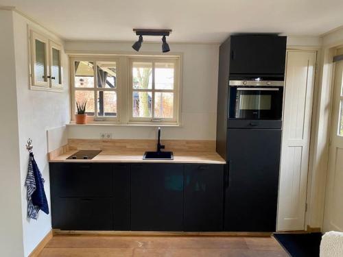 een keuken met zwarte apparatuur en een zwarte koelkast bij LooSan Lodges Gastenhuis in Reutum