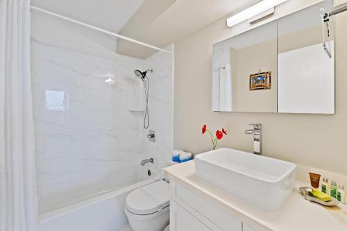 a white bathroom with a sink and a tub and a toilet at Stunning 1BR Ocean View Condo at Ilikai Marina in Honolulu