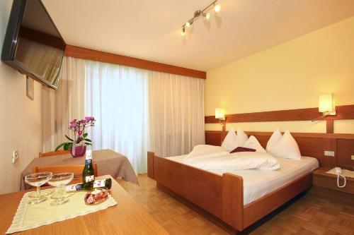 a hotel room with a bed and a table with wine glasses at Hotel Garni Savoy - new opening in Castelrotto