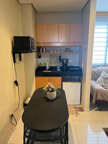 a small kitchen with a black table with flowers on it at Flat super equipado in Sao Paulo