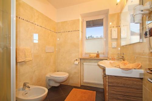 a bathroom with a toilet and a sink and a mirror at Hotel Garni Savoy - new opening in Castelrotto