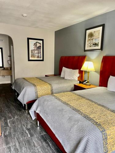 a hotel room with two beds and a lamp at American Way Inn & Suites in Memphis